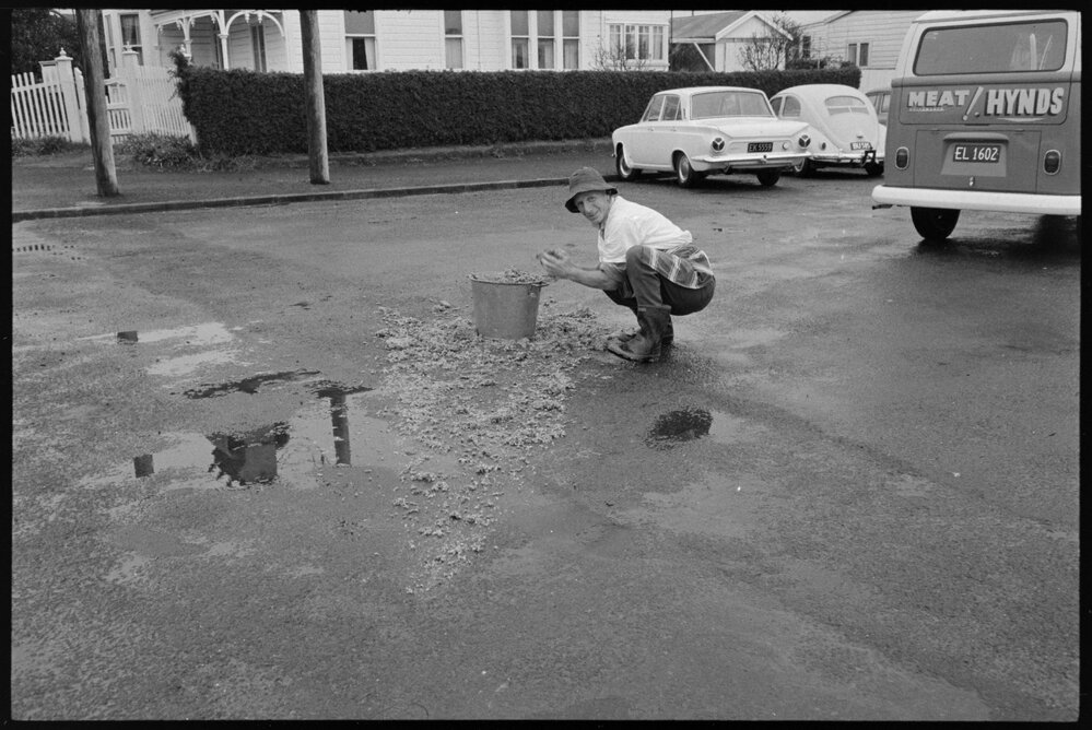 Mr A.J. Sklenars (Butcher) cleaning up mince off the road when it fell from his van
