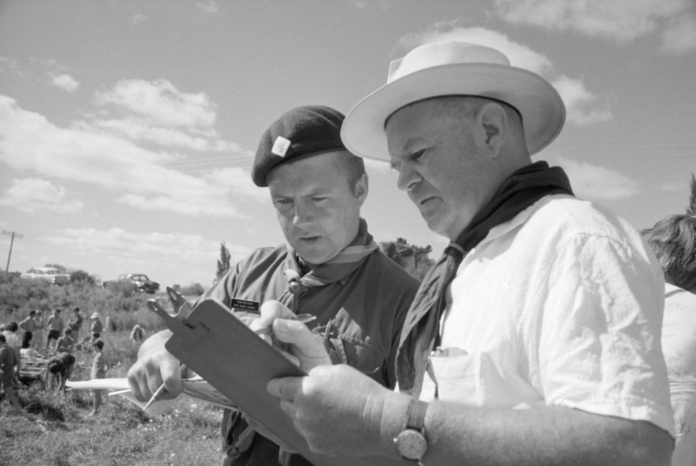 Black and white photograph of Ross Butcher and Colin Spratt looking at a clipboard at an outdoor event