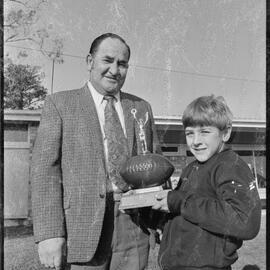 Rugby. Mr Gordon Woods presents his trophy to its first winner, Robert Walpole, at Tauranga Domain.