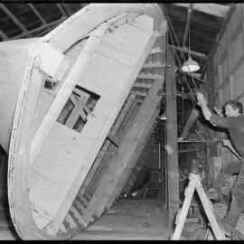 Howard Stafford helping turn a hull to an upright position using block-and-tackle.