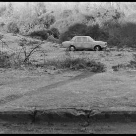 Damaged car abandoned in field.