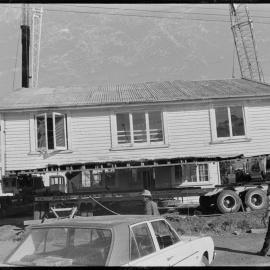 Cutting a house in half to move it from 1st Avenue to near the old Pāpāmoa garage on State Highway 2 - lowering the top half onto the trailer.