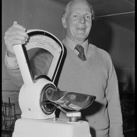 Mr Jack Wray packing up a set of scales from the Hospital Store on 18th Avenue.