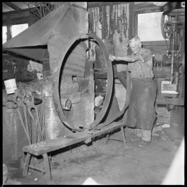 Tauranga blacksmith Mr Charlie Haua works on steel "tyre" for wagon wheel in his Grey Street smithy