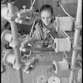 TISCO. A technician watching a dial while he winds on the coil for T.V. receiver