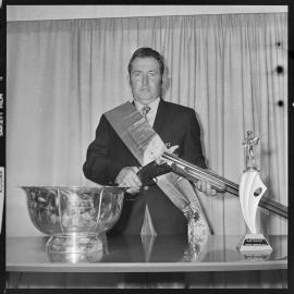 Trap shooting trophy winner poses with gun