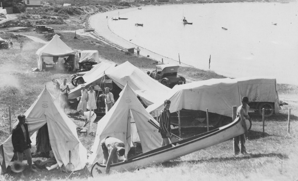 Camping at Mount Maunganui, 1931, with canoe, cars and tents.
e Ao Mārama - Tauranga City Libraries Photo 02-212
